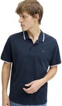 Donkerblauw poloshirt met witte strepen op de kraag en mouwen. Model draagt jeans.