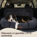 Donkergrijs, pluizig hondenbed in de kofferbak van een auto, met een Australische herder die erop ligt.