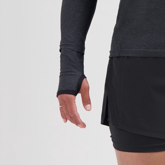 Close-up van een vrouw die een donkergrijs sportshirt met lange mouwen en duimmanchetten draagt. De onderkant van het shirt heeft een zwarte rand.