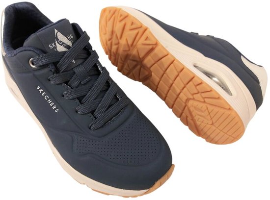 Paar donkerblauwe Skechers sneakers met beige zolen en op de zijkant het logo.
