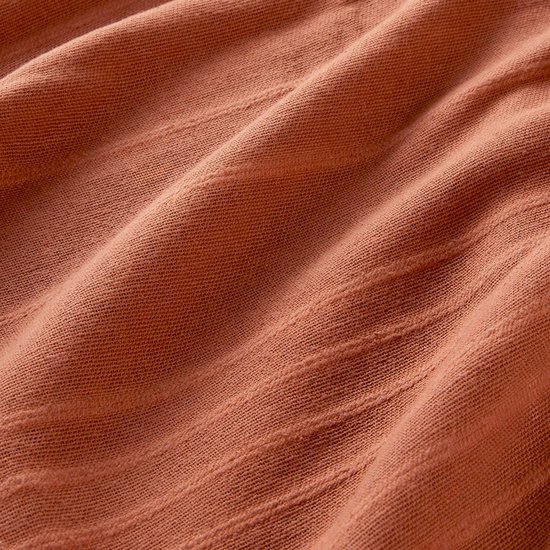 Detail van terracotta stof met fijne horizontale strepen en textuur.