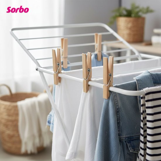 Sorbo houten wasknijpers die witte en blauwe kleding ophangen aan een droogrek. Op de achtergrond een mand.