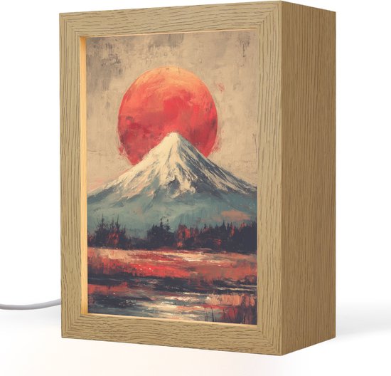 Lampe en bois avec peinture d'un sommet enneigé sous un soleil rouge, avec forêt et eau.
