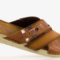 Detail van de bruine leren slipper met gekruiste banden, textiel en stiksels.