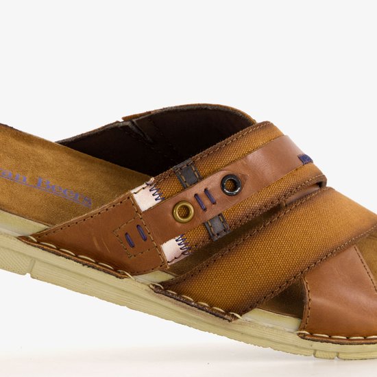 Detail van de bruine leren slipper met gekruiste banden, textiel en stiksels.