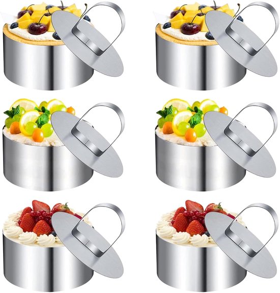 Vier RVS taartringen versierd met fruit en slagroom.