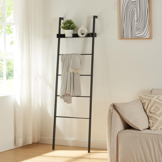 Zwarte ladderplank met opgerolde handdoek, bovenste plank met decoraties.