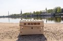 Houten Kubb kistje met touw aan de zijkanten, op zand bij een meer.