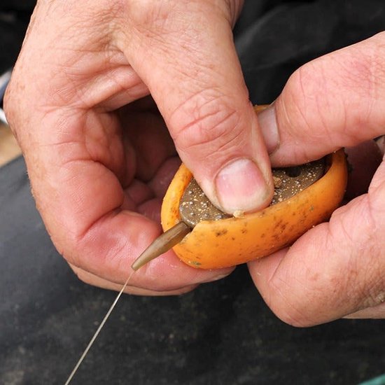 Des mains remplissent un moule de pêche orange de petits granulés.
