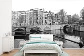Behang - Fotobehang Grachtenpanden en bruggen in Amsterdam - zwart wit - Breedte 390 cm x hoogte 260 cm