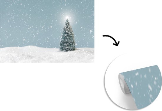 Behang - Fotobehang Een kerstboom in een besneeuwd landschap en een blauwe hemel - Breedte 525 cm x hoogte 350 cm