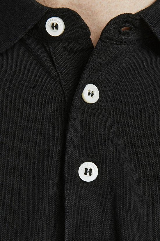 Detail van de kraag en witte knopen van een zwarte polo.