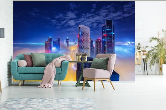 Papier peint photo en vinyle - La tour de Dubaï s'élève au-dessus des nuages dans la nuit de largeur 525 cm x hauteur 350 cm - Tirage photo sur papier peint (disponible en 7 tailles)