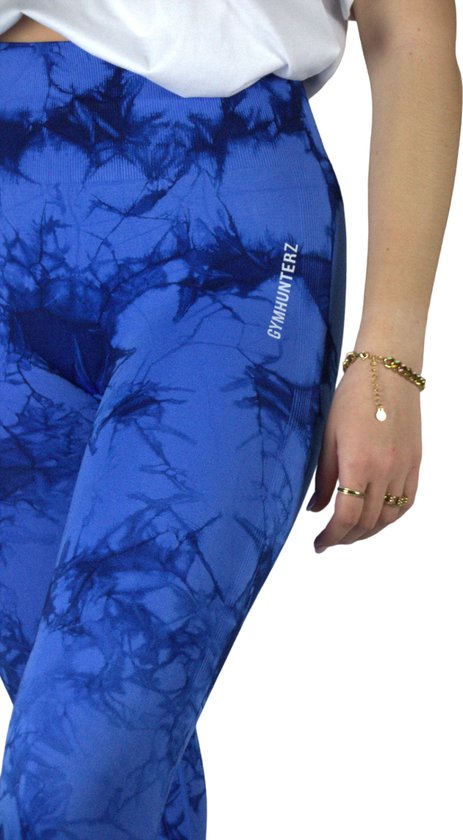 Close-up van blauwe tie-dye sportlegging met wit GYMHUNTERZ logo op de heup.