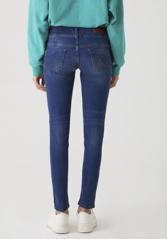 Achterkant van een model met een turquoise trui en witte sneakers, draagt een donkerblauwe, nauwsluitende jeans.