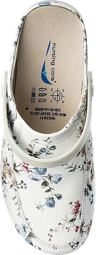 Binnenaanzicht van een witte klomp met bloemenprint. De binnenzool toont het logo 'nursing care' en certificeringssymbolen.