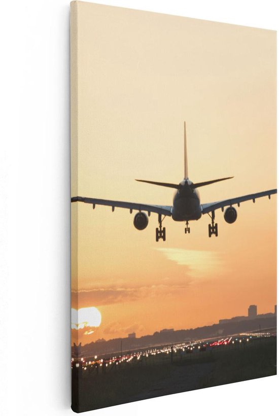 Avion atterrissant au coucher du soleil, avec les lumières de la piste au premier plan.