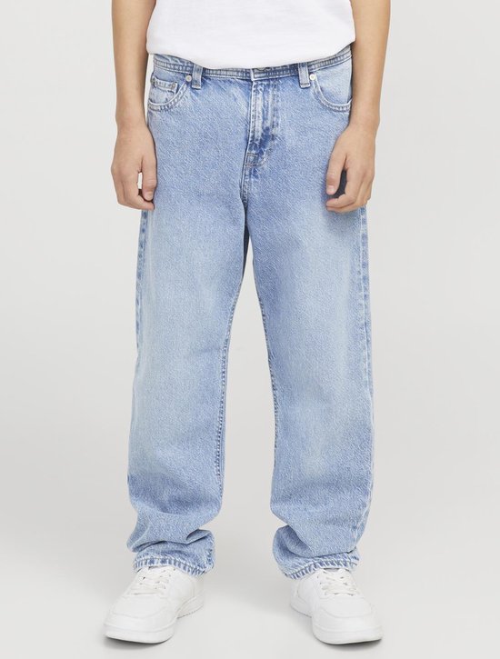 Jongen draagt een wijde, lichtblauwe spijkerbroek met witte sneakers.