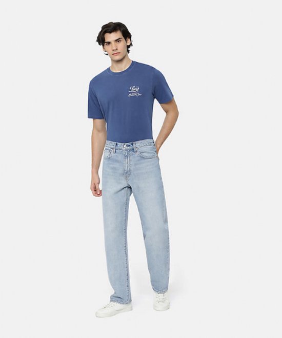 Homme portant un jean Levi's 568 Stay Loose bleu clair et un t-shirt bleu avec inscription blanche.