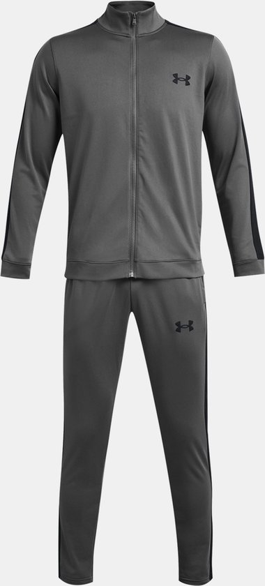 Volledig grijs Under Armour trainingspak met zwarte accenten op de zijkant van het jack en de broek. Logo op de borst en het been.