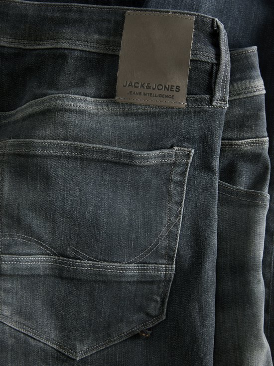 Detail van de achterkant van een donkere jeans met bruin leren merklabel.