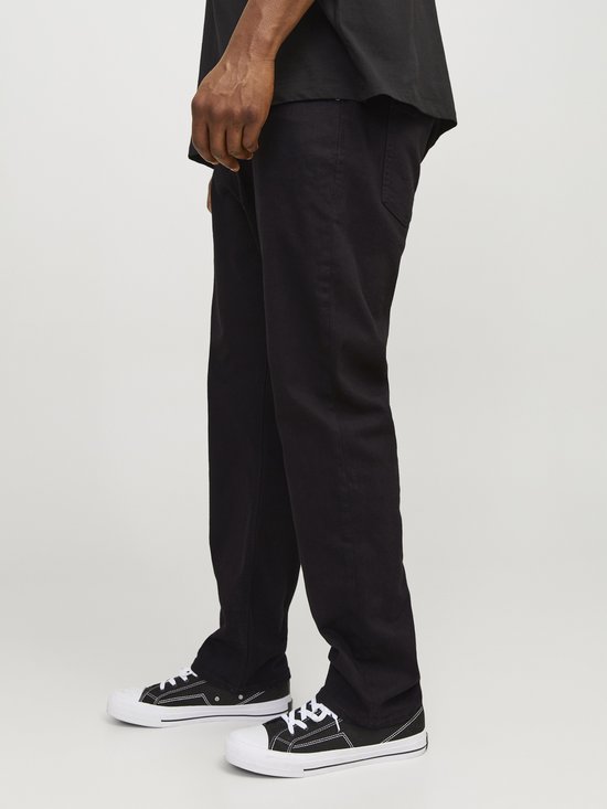 Detail van de broekspijpen van een zwarte jeans met witte stiksels.