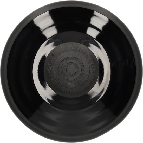 Onderkant van een glimmend zwarte fluitketel van Le Creuset met het logo.