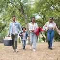 Familie wandelt in het park met een grijze koelbox.
