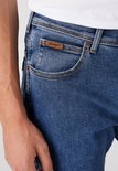 Detail van blauwe Wrangler jeans met bruin label op de zak.