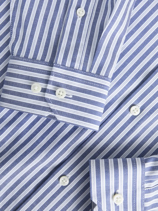 Detailopname van een blauw-wit gestreept overhemd met witte knopen op de manchetten.