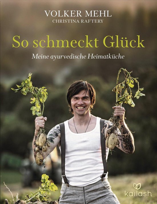 Een man met tatoeages op zijn armen draagt een wit hemd met bretels en linnen broek. Hij lacht en houdt twee aardappelplanten vast met wortels.