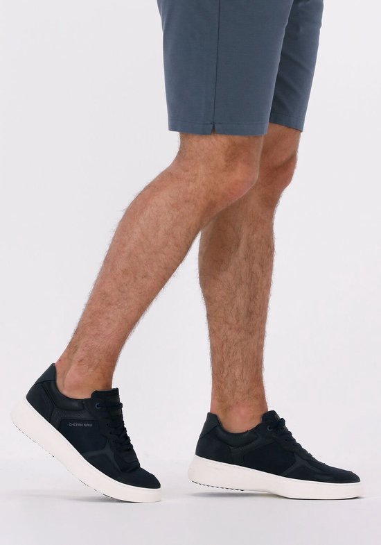 Man met donkerblauwe G-Star Raw sneakers aan, met korte broek. Witte zolen, suède, mesh en lederen details.
