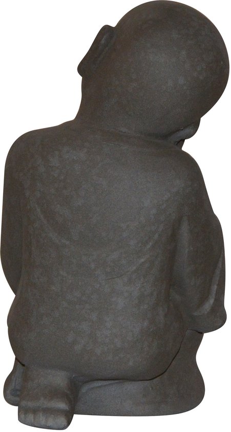 Vue arrière d'une statue de Bouddha enfant en pierre gris foncé, assise en tailleur, tête sur la main.