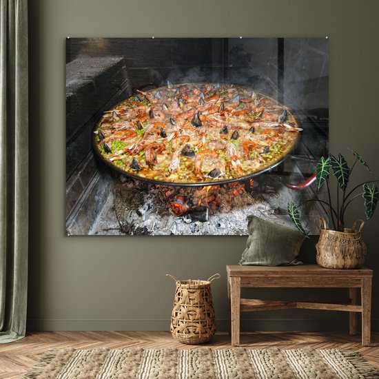 MuchoWow® Glasschilderij 160x120 cm - Schilderij acrylglas - Zeevruchtenrijst gekookt in een brandhou. Paella is een van de traditionele gerechten van Spanje - Foto op glas - Schilderijen