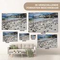 Meerdere maten van een glazen schilderij met pinguïns op het strand, naast een bank.