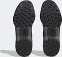 De onderkanten van twee zwarte wandelschoenen met een robuust profiel en 'TRAXION' op de zool.