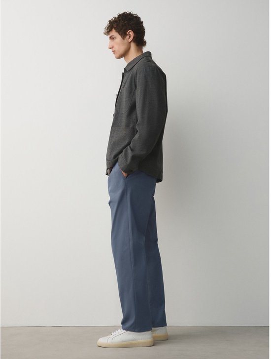 Man in relaxte blauwe chino broek en donkergrijs jasje.