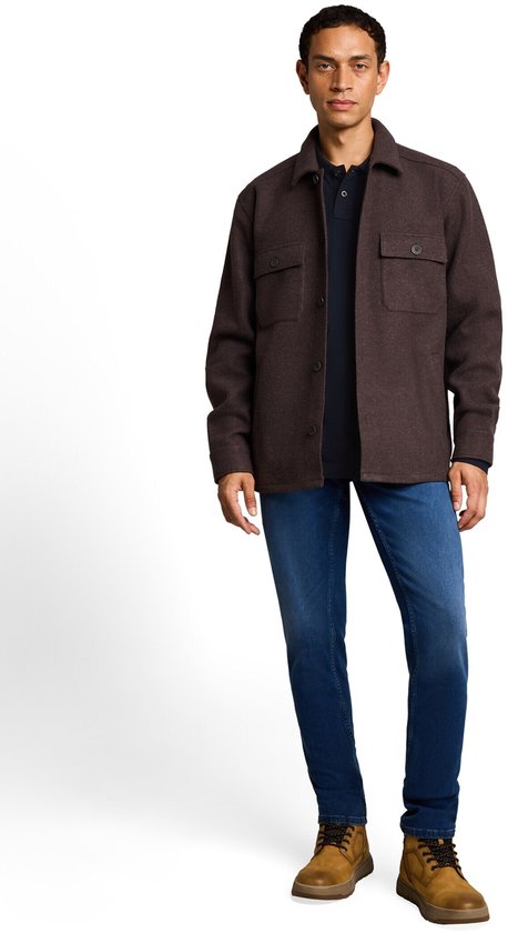 Man draagt een donkerblauw poloshirt met lange mouwen, bruine jas en jeans.