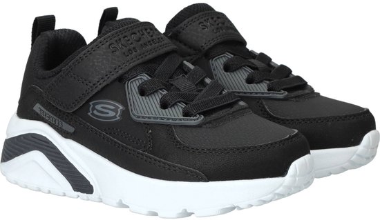 Paar zwarte Skechers sneakers met klittenband en veters. Witte zolen met grijze accenten. Logo's zichtbaar.