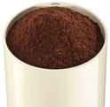 Een beige koffiemolen gevuld met gemalen bruine koffie.