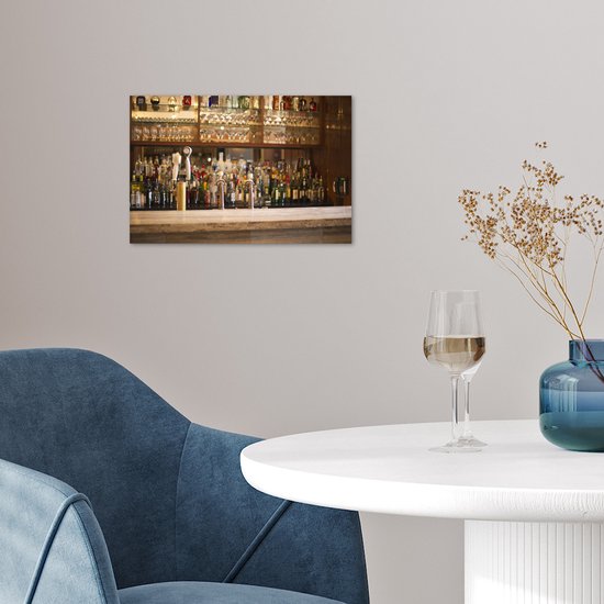 Poster met flessen drank en glazen op een bar, in een woonkamer bij een stoel met een glas wijn.