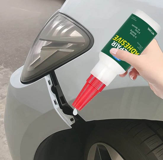 Een hand met een flesje TLVX plastic reparatielijm repareert de voorbumper van een auto.