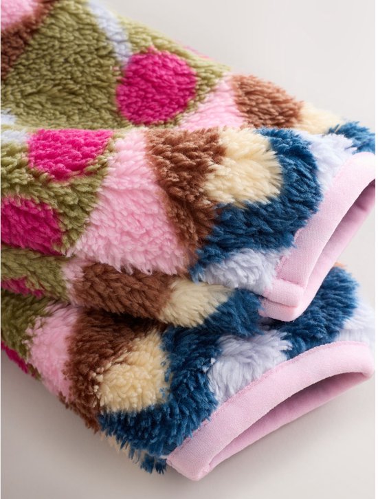 Close-up van de mouwen van een fleece babyjasje met een kleurrijk patroon van kersen en harten.