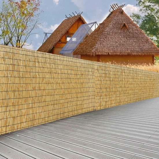 Rieten privacyscherm voor een rustiek huis met rieten dak en een houten terras.