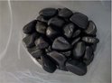 Zwarte, glanzende kiezels in een plastic zak, gezien van bovenaf.