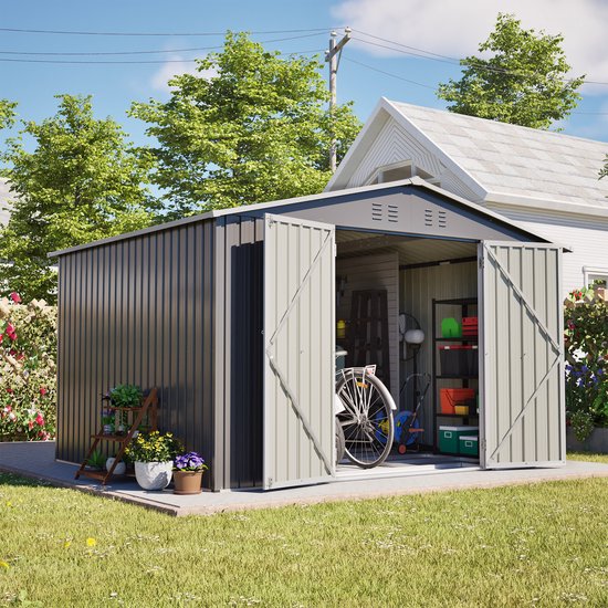 Grijze tuinschuur met zadeldak, dubbele deuren. Een fiets en opbergbakken staan in de open schuur. Plantenbakken staan buiten.
