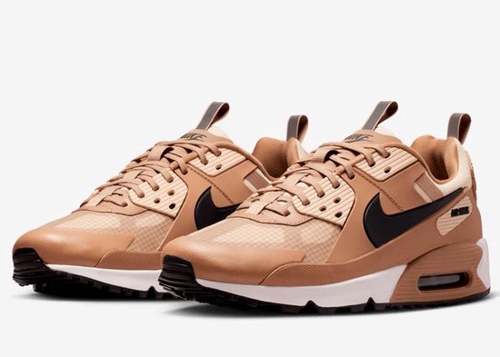 Twee lichtbruine Nike Air Max 90 Drift sneakers met zwarte swooshes, naast elkaar.