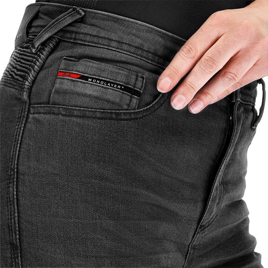 Sluiting van de grijze dames motorjeans met een rood 'MONOLAYER' logo op de zak.