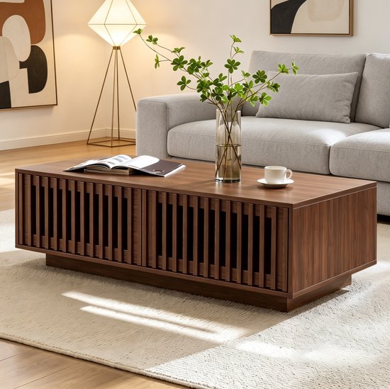 Table basse couleur noyer avec façade à lattes dans un salon à côté d'un canapé gris.