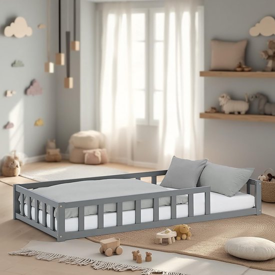 Grijze houten Montessori-peuterbed geplaatst in een kinderkamer met houten speelgoed op de vloer.
